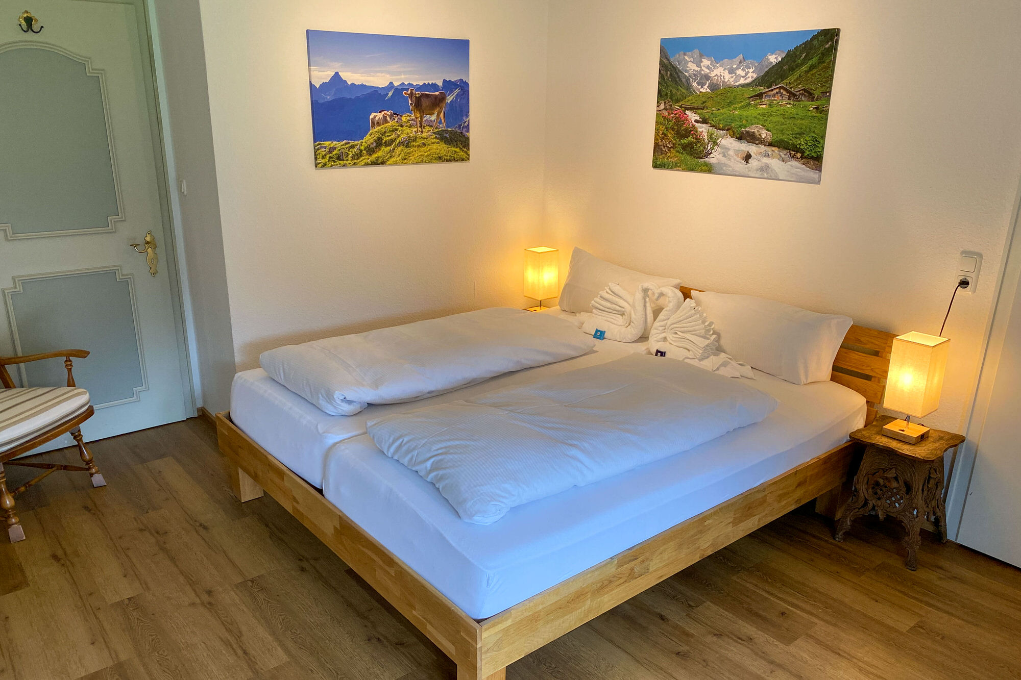 Schlafzimmer mit Doppelbett, Nachttischen und Alpinmotiven an der Wand.