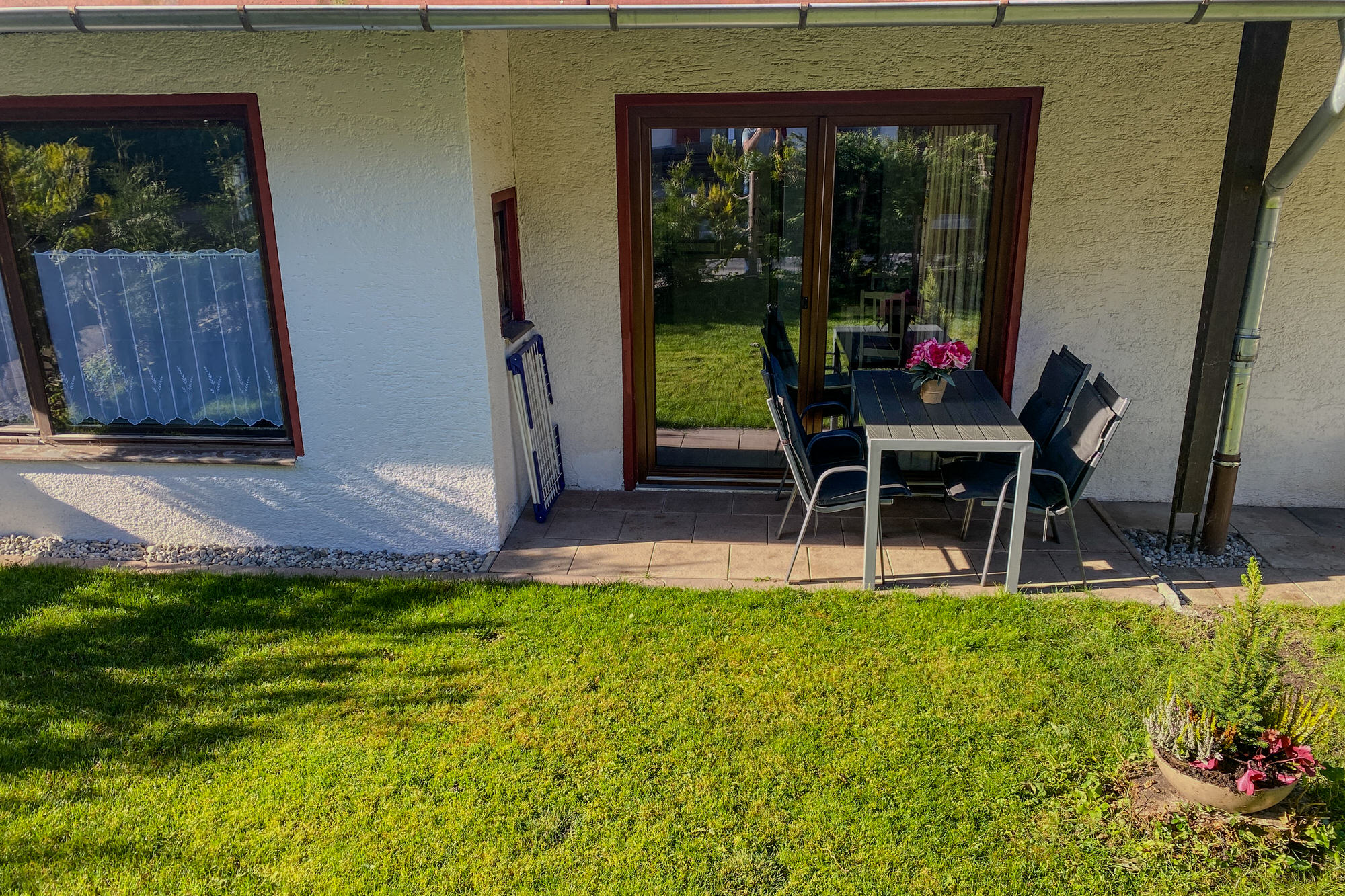 Terrasse mit Gartentisch und Blumen vor der Ferienwohnung
