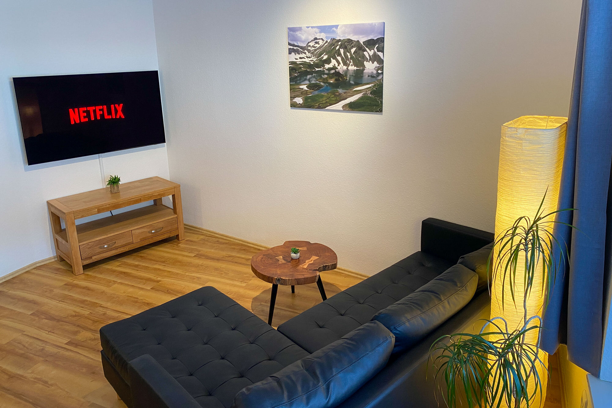 Modernes Wohnzimmer mit schwarzem Sofa und Netflix-TV